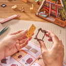 Eine Person baut ein Möbelstück aus dem Robotime A-Frame Cabin zusammen