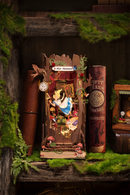Atmosphärischer Eindruck der Robotime Alice Adventure Book Nook zwischen zwei Büchern in einem waldigen Bücherregal