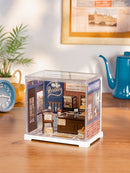 Atmosphärische Präsentation der Robotime Butter Bakery House, Miniatur- Bäckerei aus Kunststoff in einer kleinen Vitrine