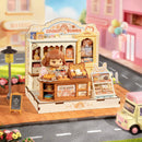 Atmosphärische Präsentation der Robotime Cookii Bunny’s Cookie Shop, Miniaturhaus einer Keksladen mit Cookii Bunny hinter der Theke