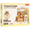 Vorderseite der Verpackung der Robotime Cookii Bunny’s Cookie Shop, Miniaturhaus einer Keksladen mit Cookii Bunny hinter der Theke
