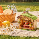 Robotime Fluffy Grove zusammen mit Blumen und einem Brotkorb auf einer Picknickdecke
