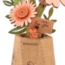 Details einer Blume und der Vase mit einem kleinen Schild der Robotime Light Orange Gerbera