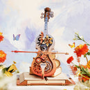 Atmosphärische Präsentation des Robotime Magic Cello – Symphony of Gorgeous Dreams mit Schmetterlingen, Blumen und blauem Himmel im Hintergrund
