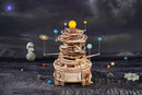 Das Robotime Mechanical Orrery mit Dekoration drum herum und einer Mondlandschaft im Hintergrund