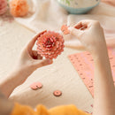 Eine Person bastelt gerade die Blume der Robotime Pink Dahlia