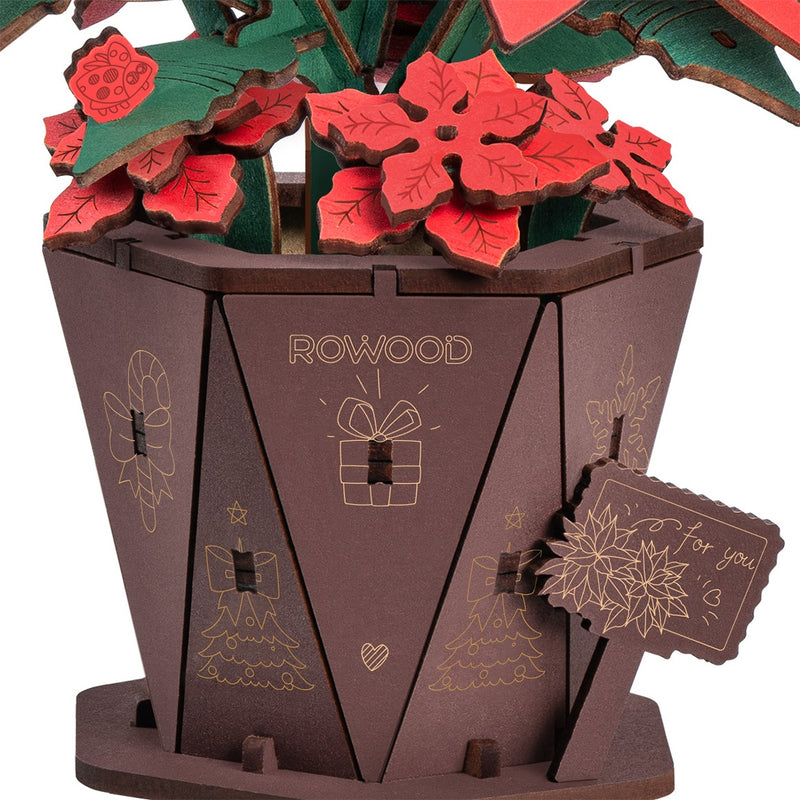 Nahaufnahme des Topfes, des Schildchens und einiger kleiner Blümchen der Robotime Poinsettia