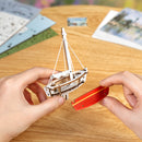 Eine Person baut eines der Segelboote aus dem Set Robotime Red Boats zusammen