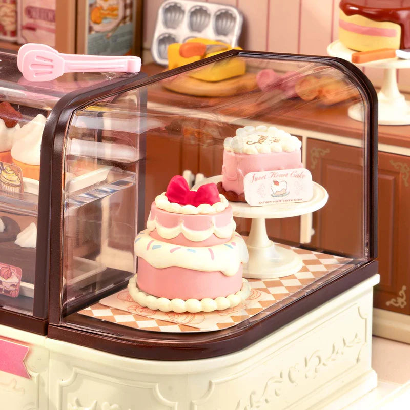 Nahaufnahme von zwei Torten im Schaufenster des Robotime Tasty Cake Shop